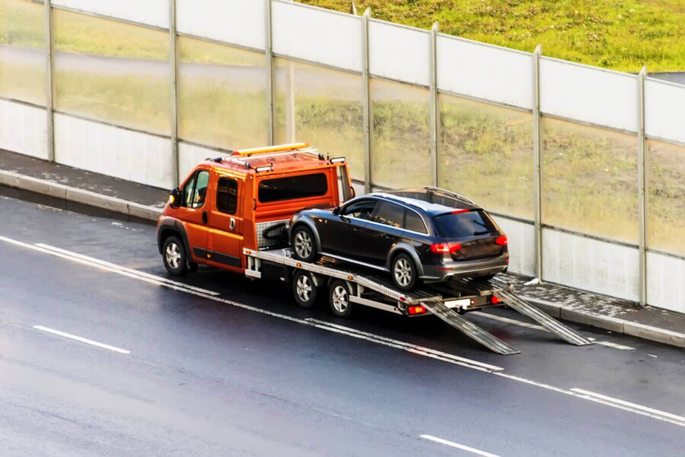 Flatbed recovery truck transporting a stranded vehicle