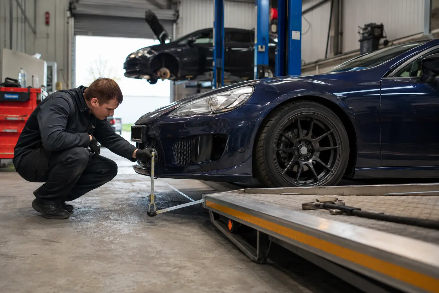 Technician checking sports car clearance before flatbed loading